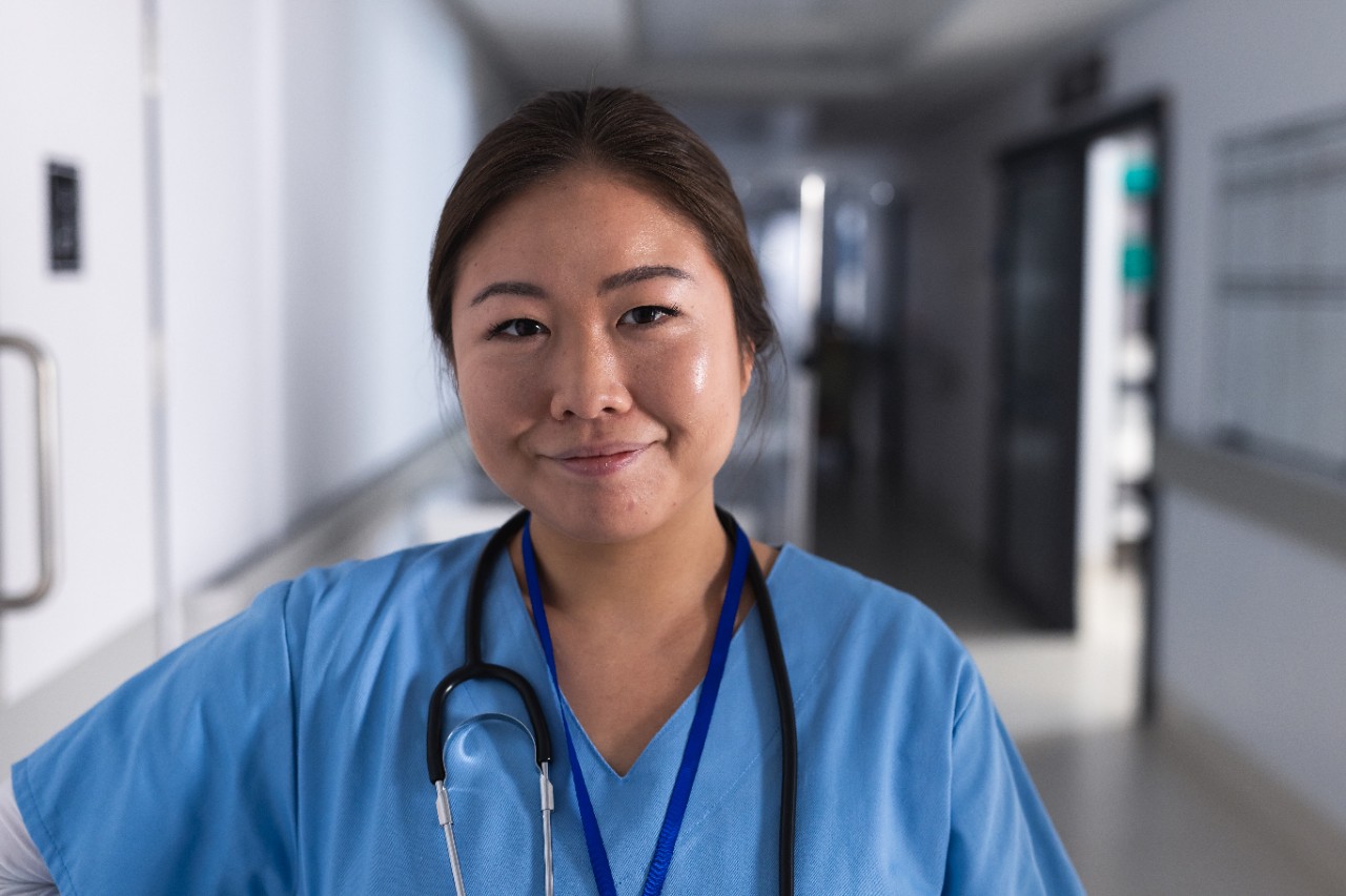 Portrait of happy asian female doctor in hospital corridor